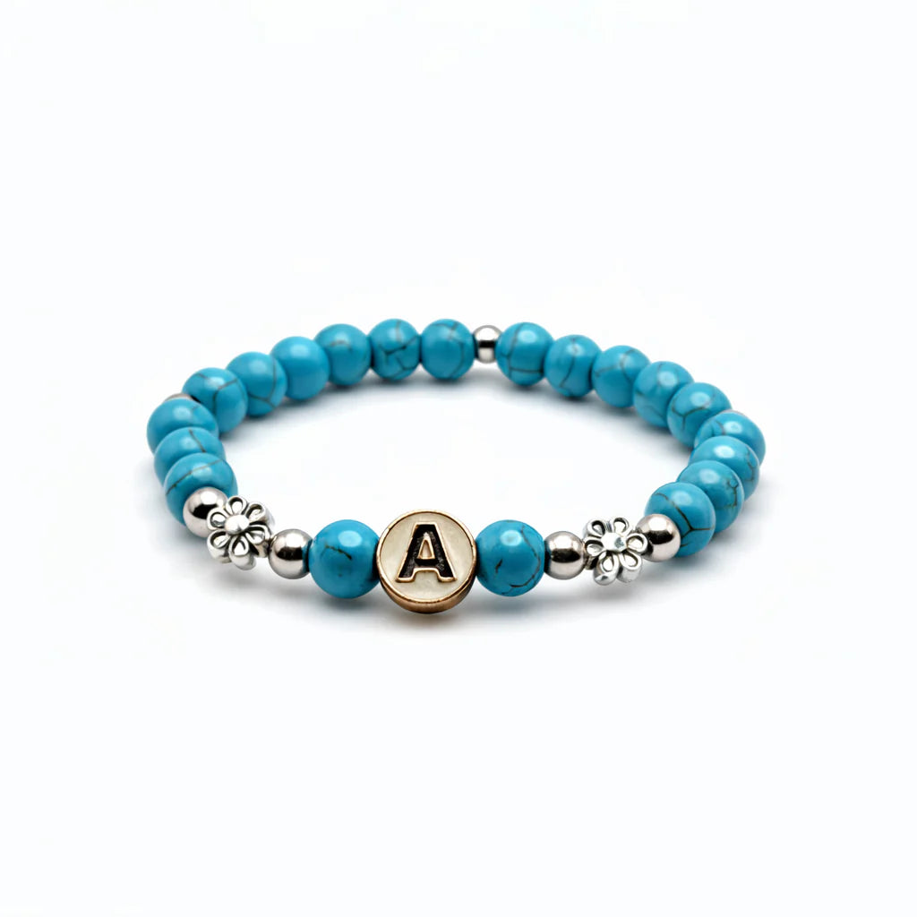Turquoise marbled Howlite bead bracelet with gold letter charm and flower spacer accents on white background
