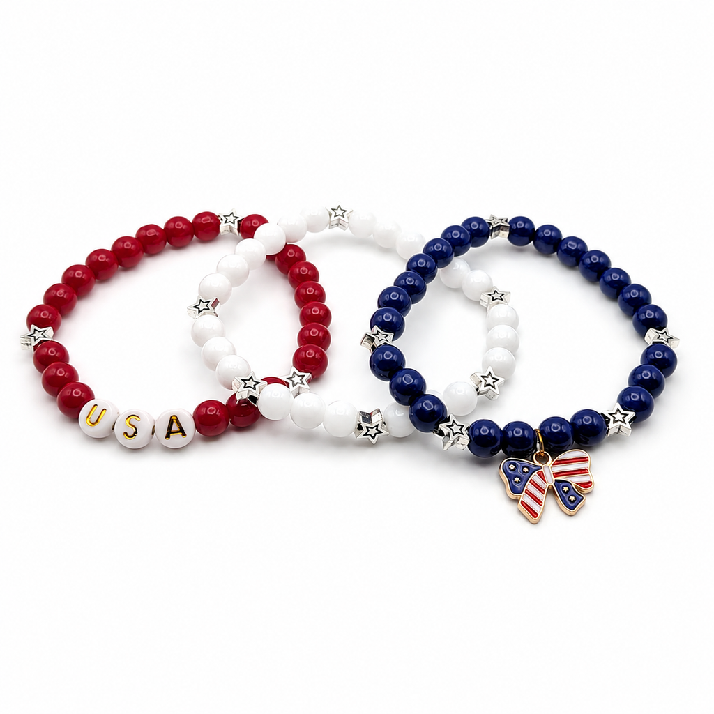 Three-piece patriotic bracelet set with red, white, and blue 6mm glass beads, star accents, USA letter beads, and an American flag bow charm arranged together