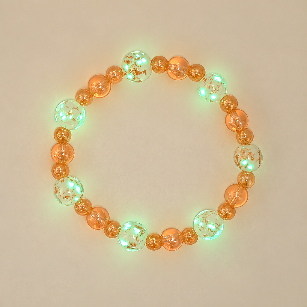 Golden Firefly glow-in-the-dark bracelet showing green glowing lampwork beads alongside champagne-toned glass beads in low light