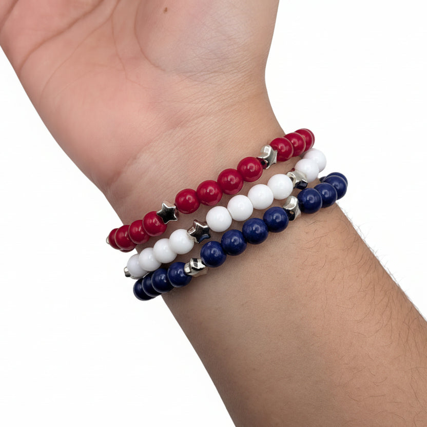 Stacked red, white, and blue patriotic bracelets worn on wrist featuring star accents for Independence Day and summer celebrations
