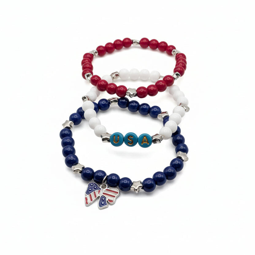 Three-piece patriotic bracelet set with red, white, and blue 6mm glass beads, star accents, USA letter beads, and an American flag bow charm arranged together