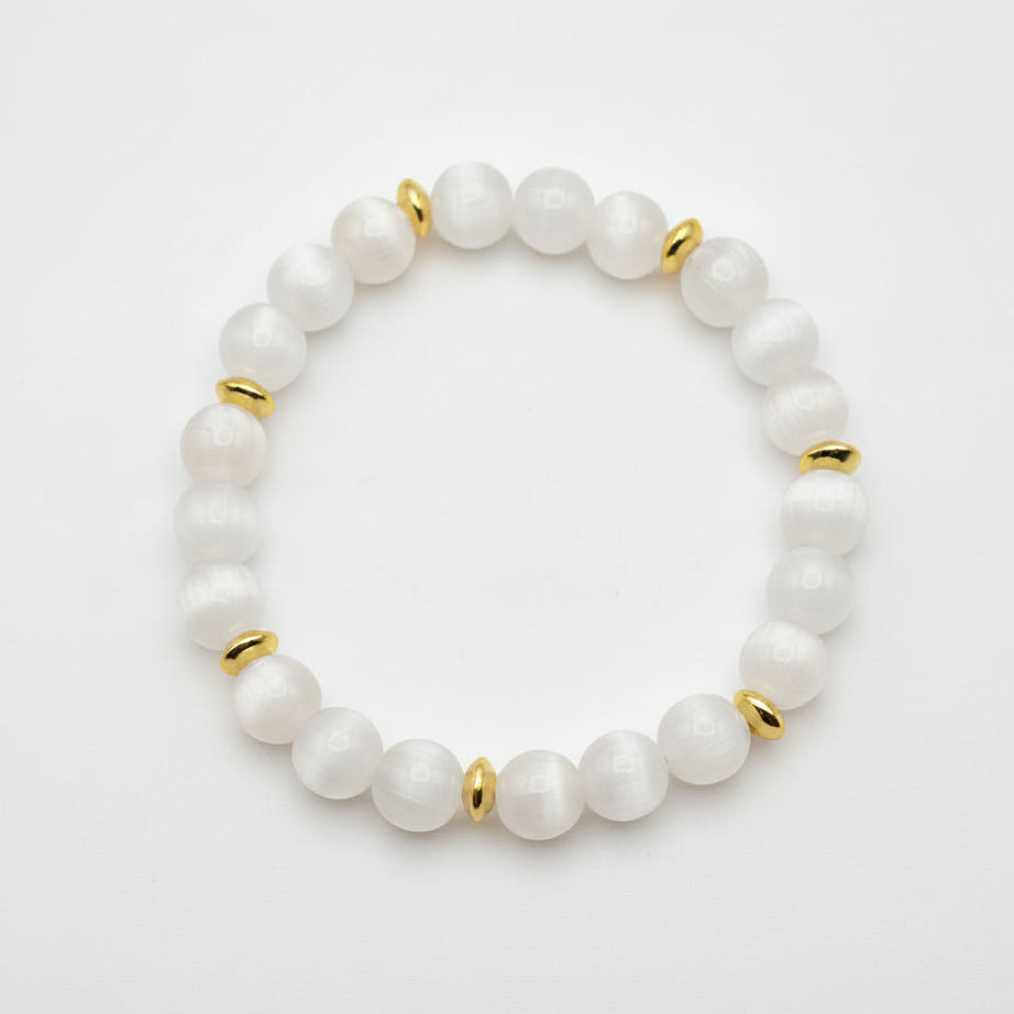 UV color changing bracelet with photochromic cat’s eye beads under room light, appearing cream-white with gold spacer beads and stretch cord